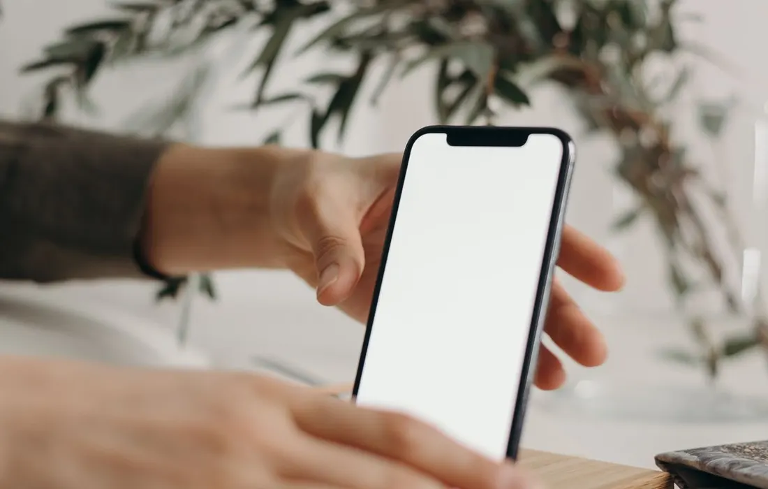 Hands holding a smartphone indoors.