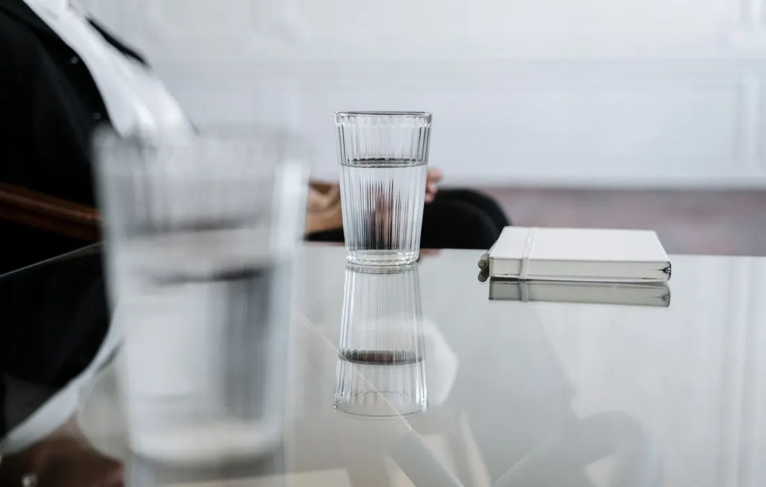 A glass of water and a notebook on a table.