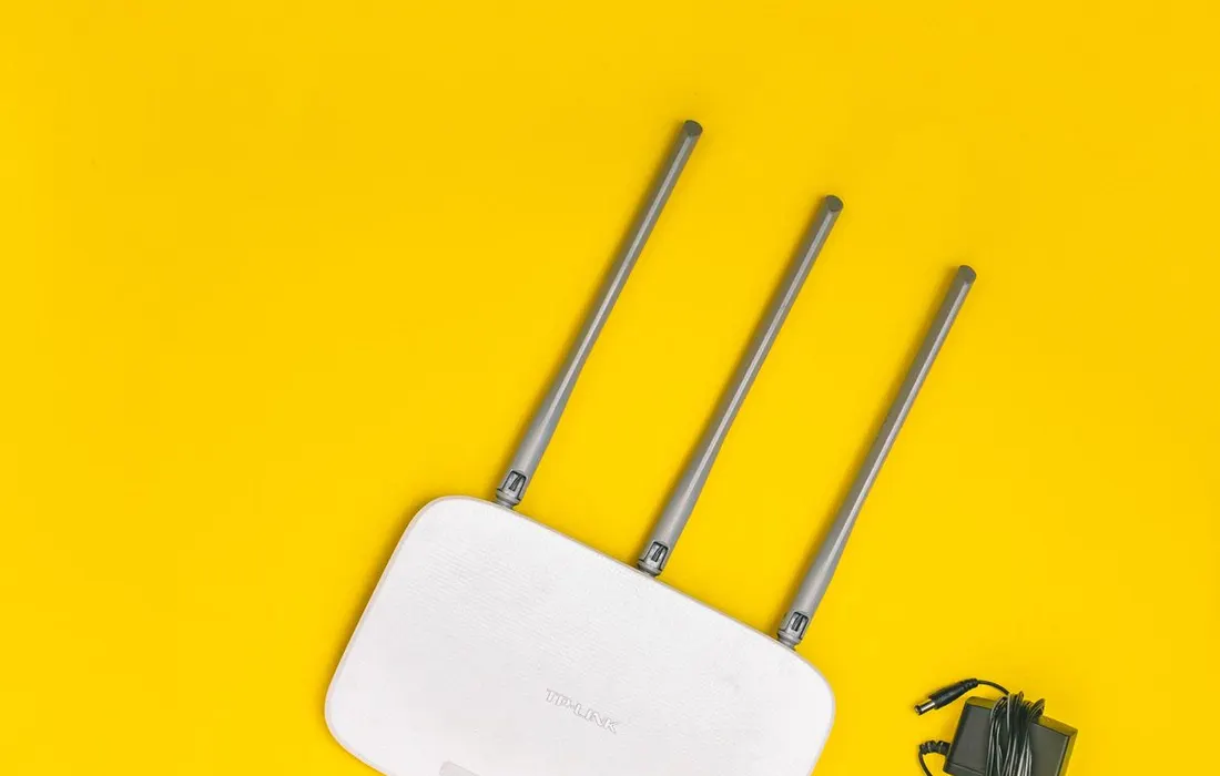 A white wireless router with aerials and connected cables.