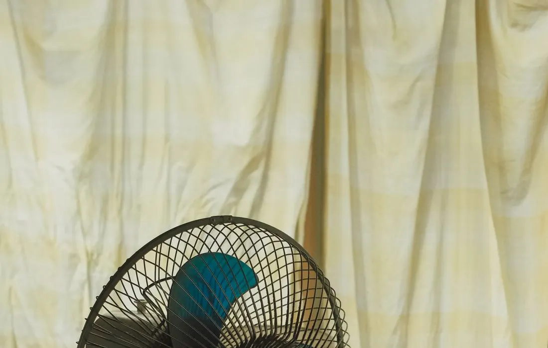 A desk fan beside a sunlit window.