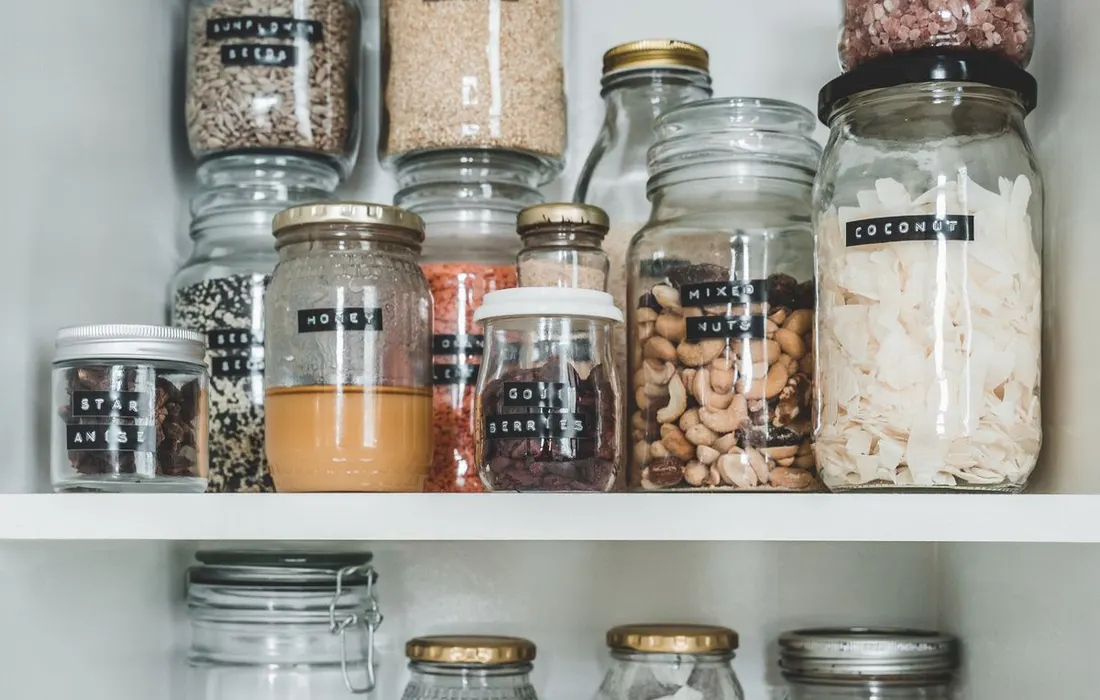 Labelled glass jars arranged on pantry shelves.