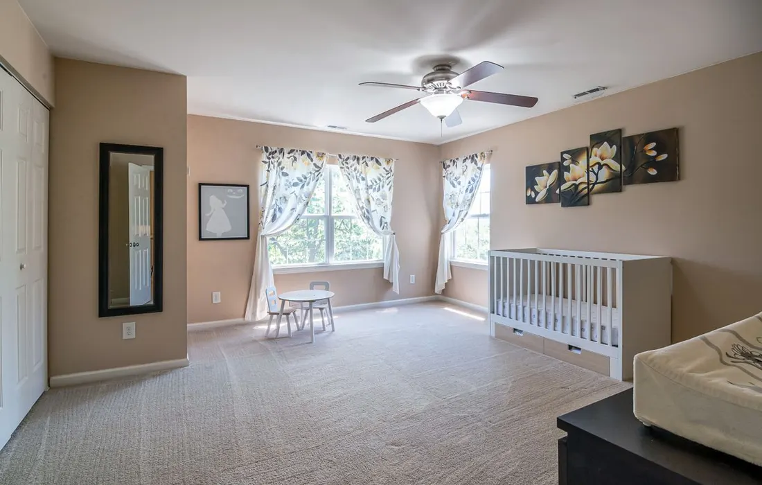 A nursery room with a cot, armchair and storage furniture.