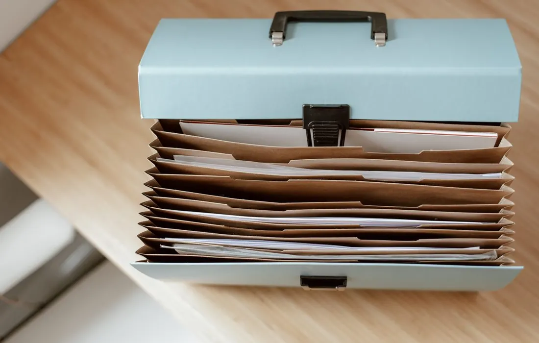 A document briefcase with papers on a wooden table.