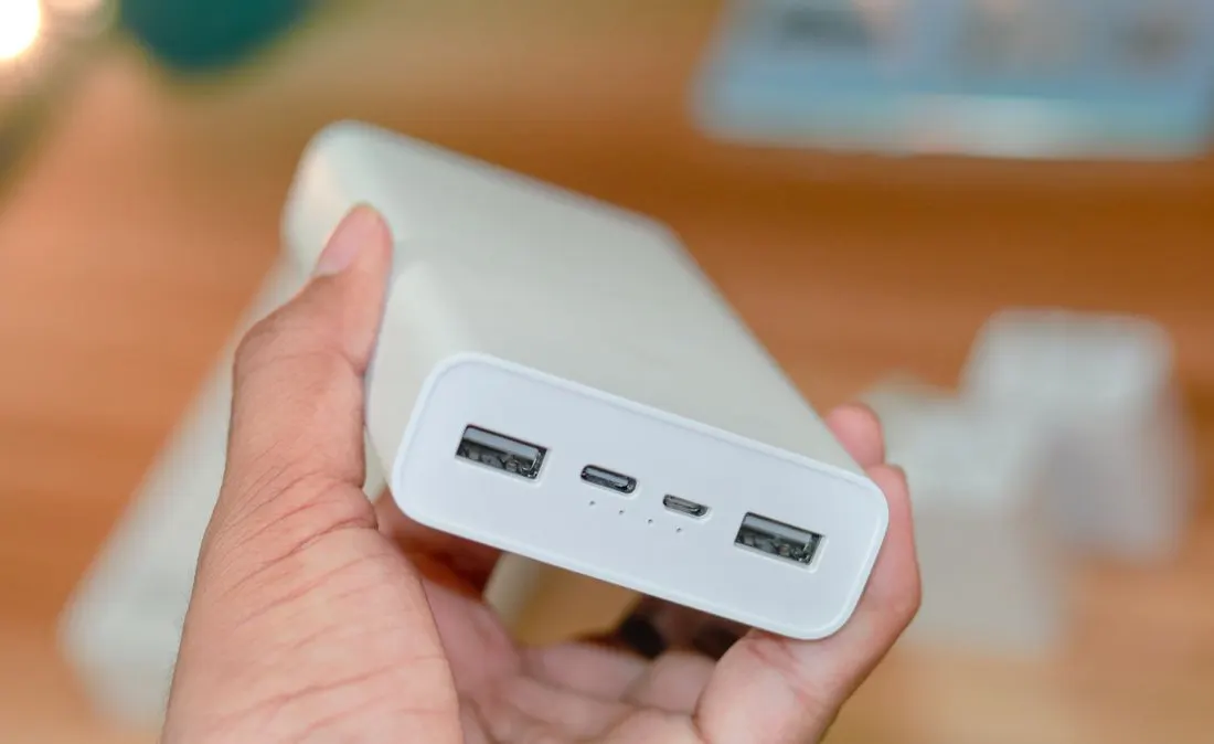 A hand holding a portable power bank with its USB ports visible.