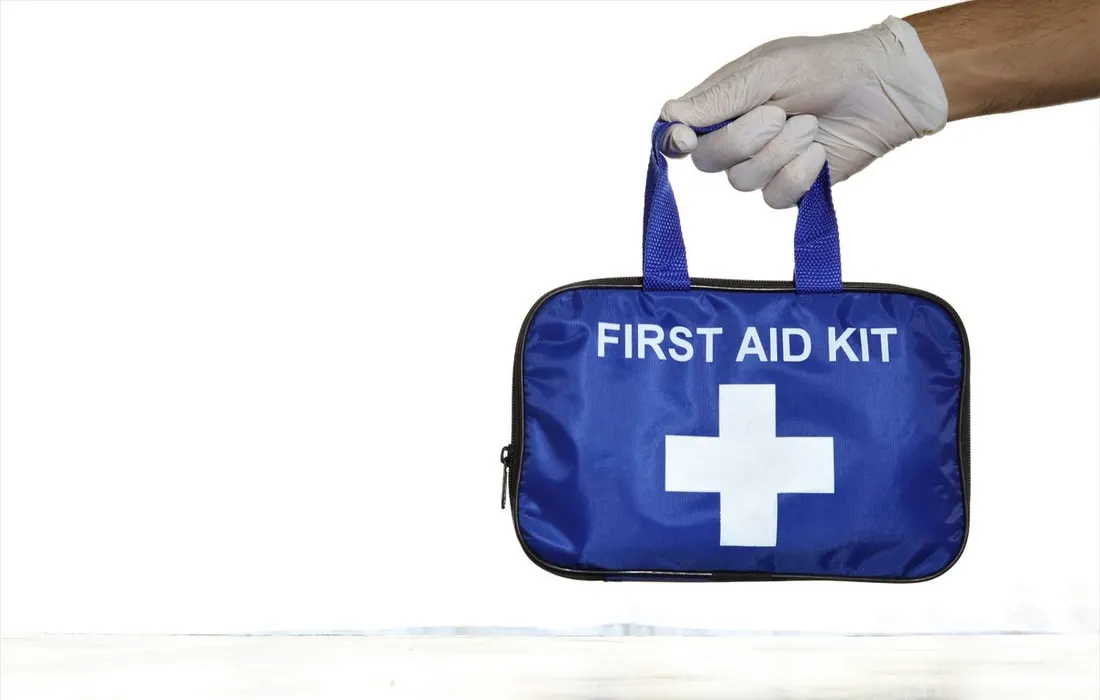 A hand holding a blue first aid kit