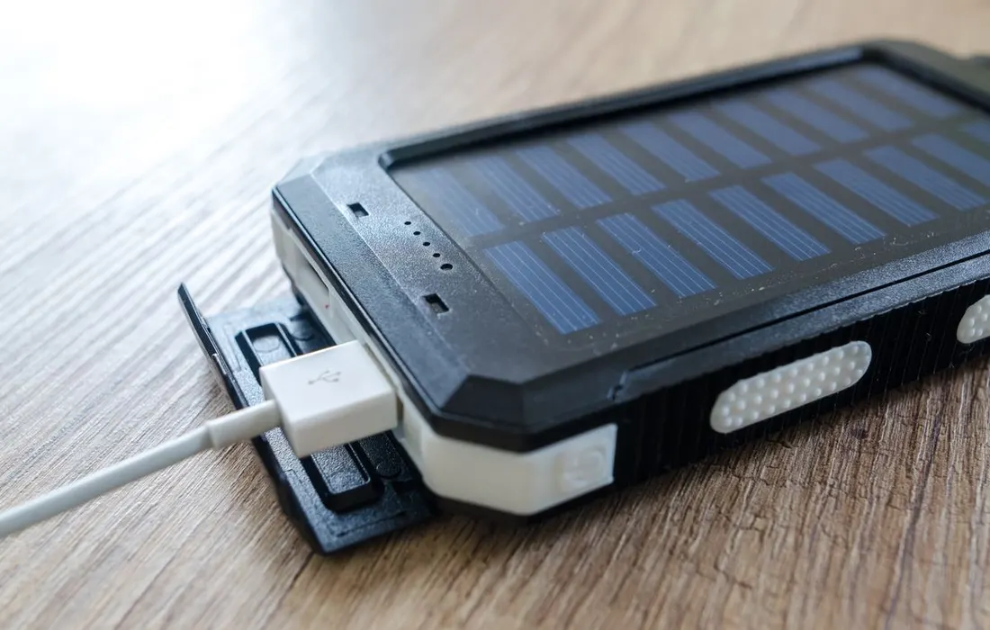 A portable solar charger with a USB cable on a wooden surface.