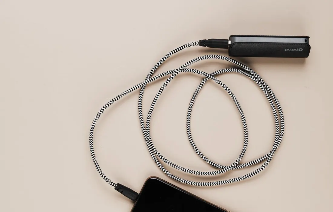 A phone and power bank connected by a coiled charging cable.
