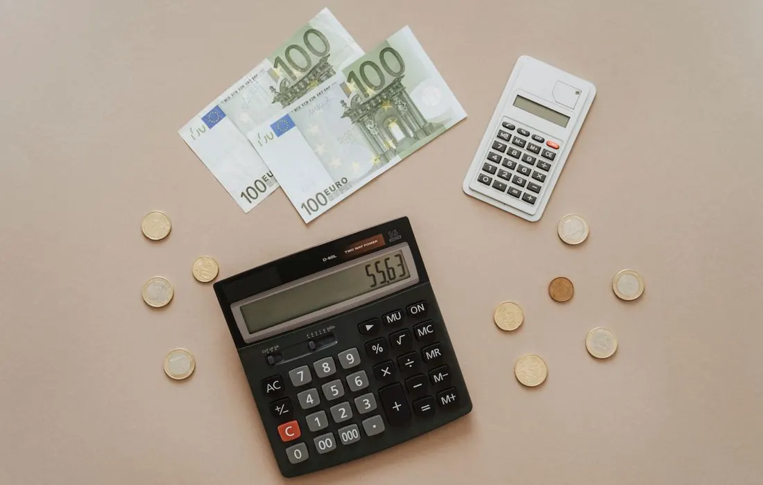 A calculator beside euro coins and banknotes.