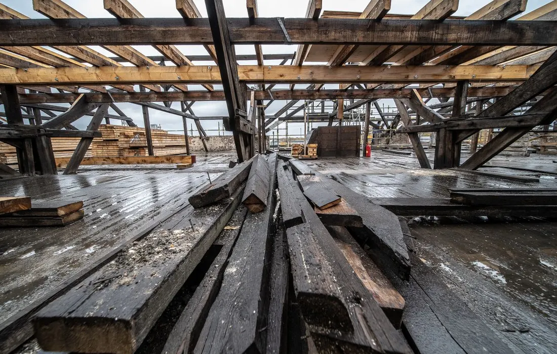 Rain-soaked construction site with exposed wooden beams and timber materials.