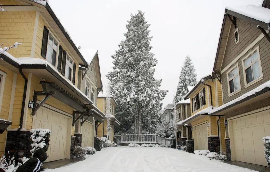 Picturesque view of houses on a snowy street with a winter landscape.