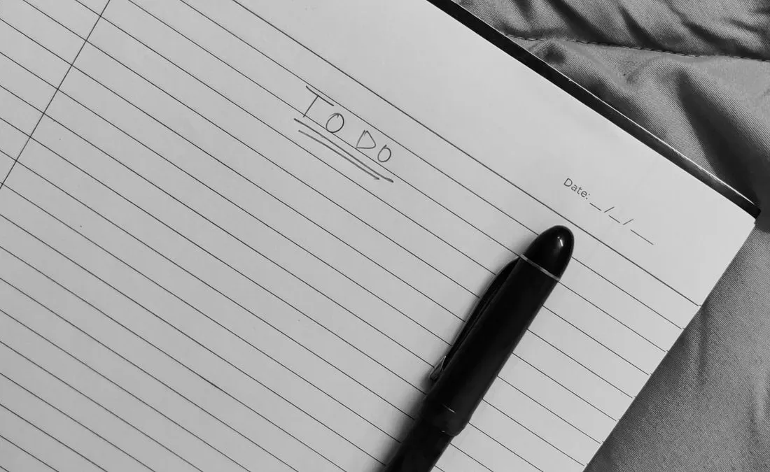 A pen resting on an open notebook with a to-do list.