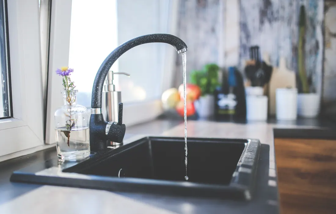 Water running from a kitchen tap into a sink.