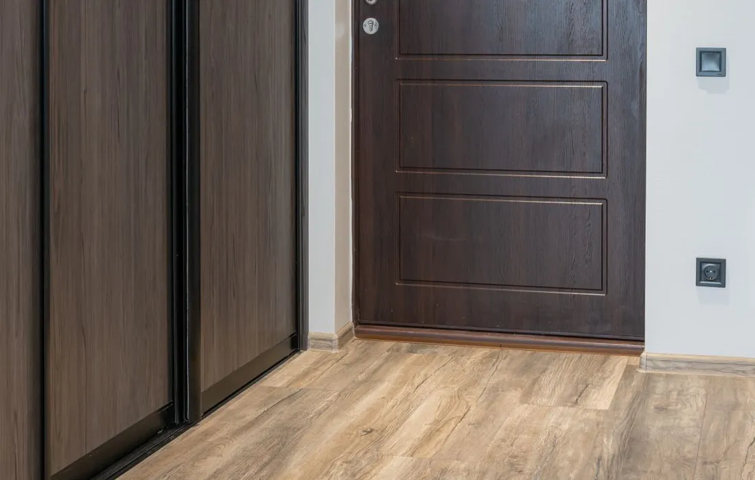 A clear interior hallway leading to a closed entrance door.