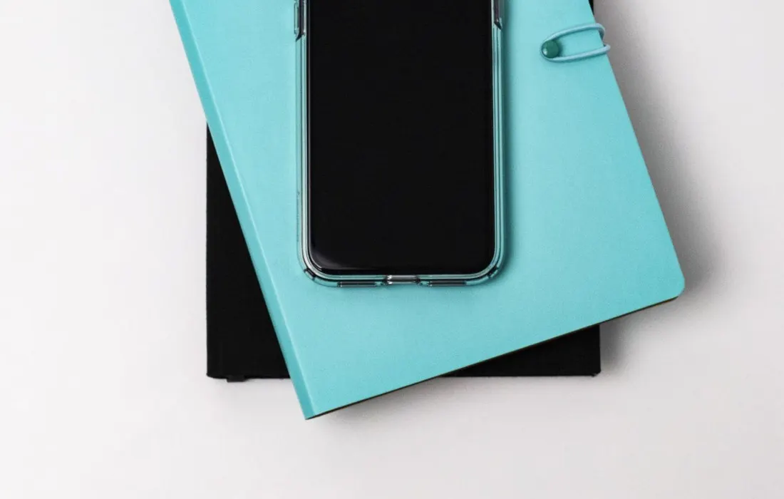 A smartphone resting on a stack of notebooks.
