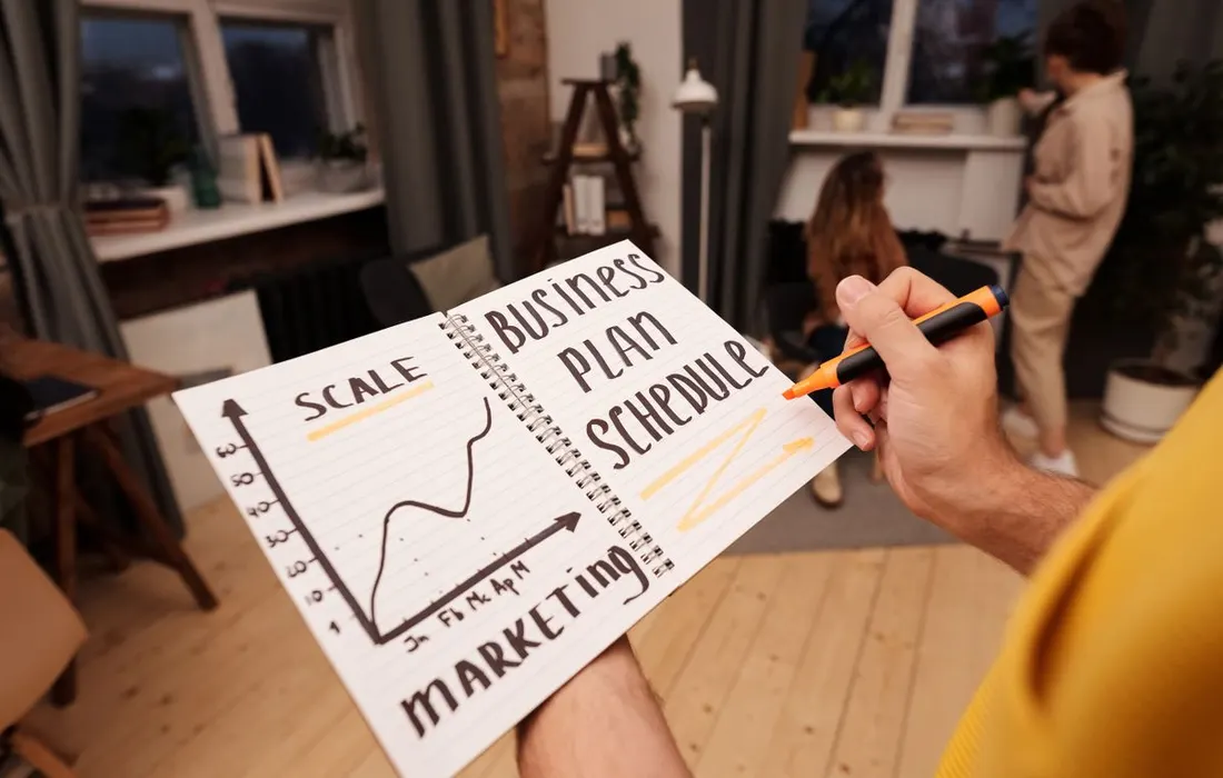 Hands holding a notebook containing written plans.