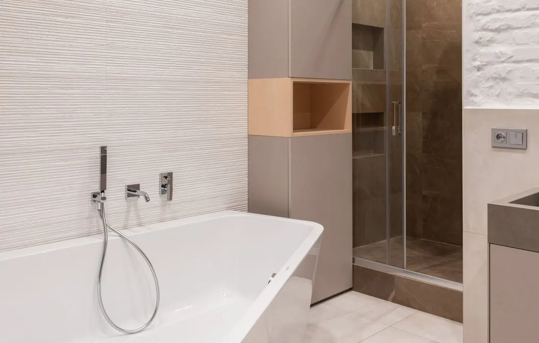 A bathtub and shower in a bright bathroom.