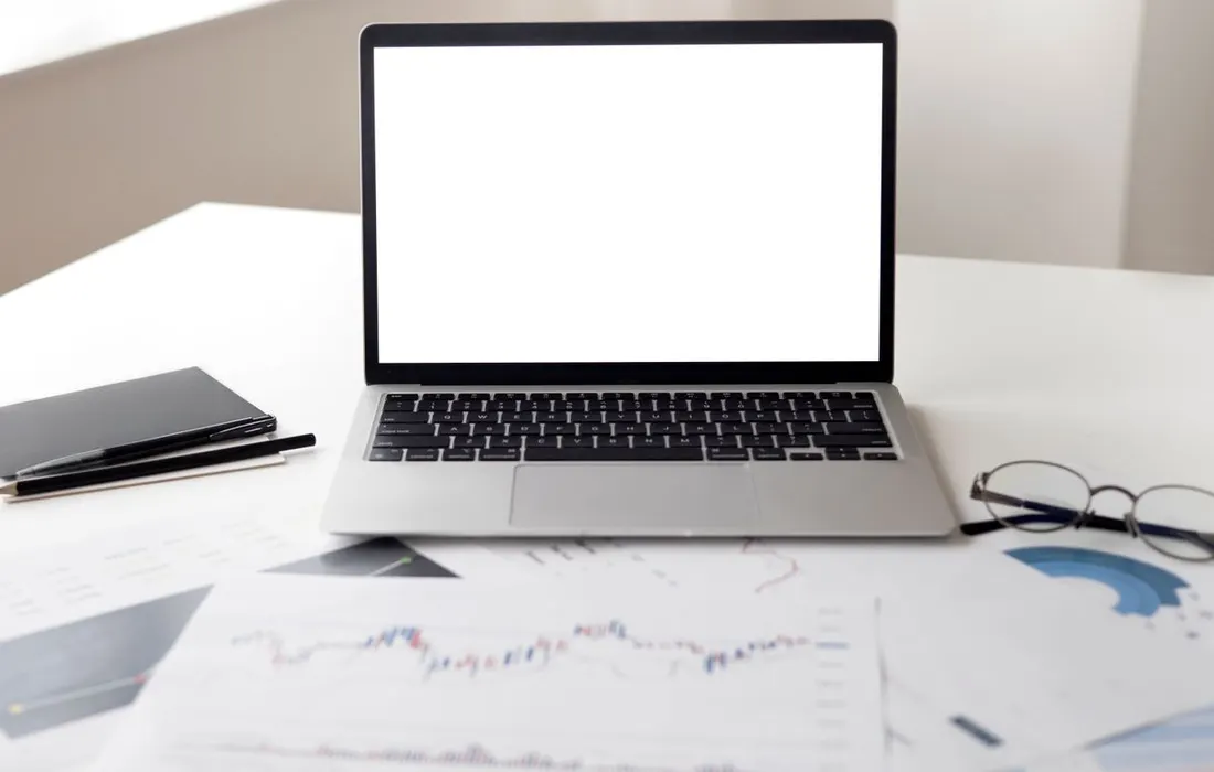 A laptop and financial paperwork arranged on a desk.
