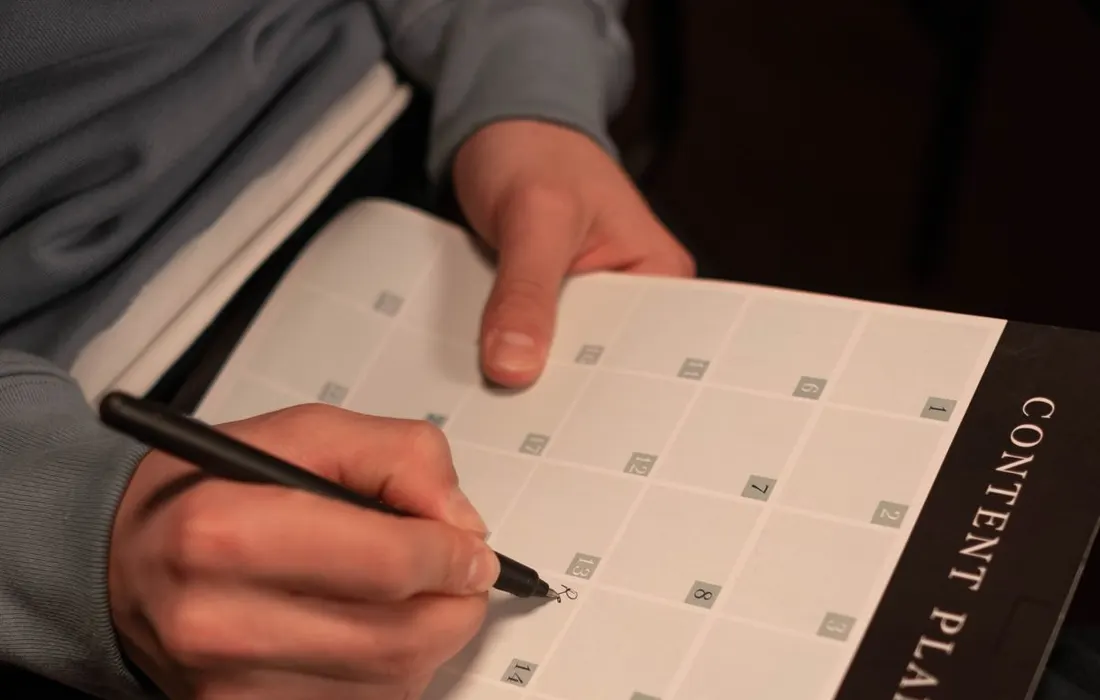 A hand adding notes to a paper planner.