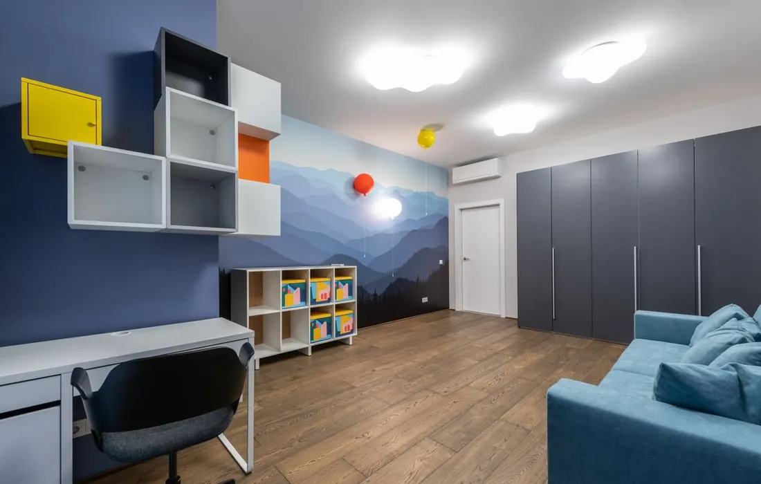 A shared living area with a sofa, desk and shelving.