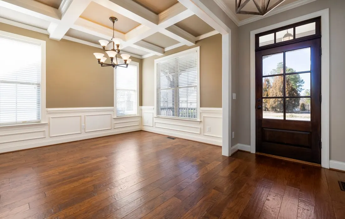 An unfurnished living room with wooden flooring and large windows.