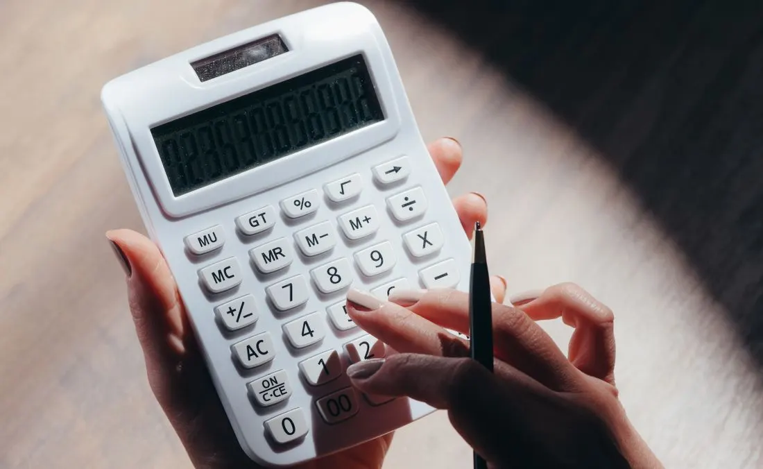 Hands using a calculator and pen.