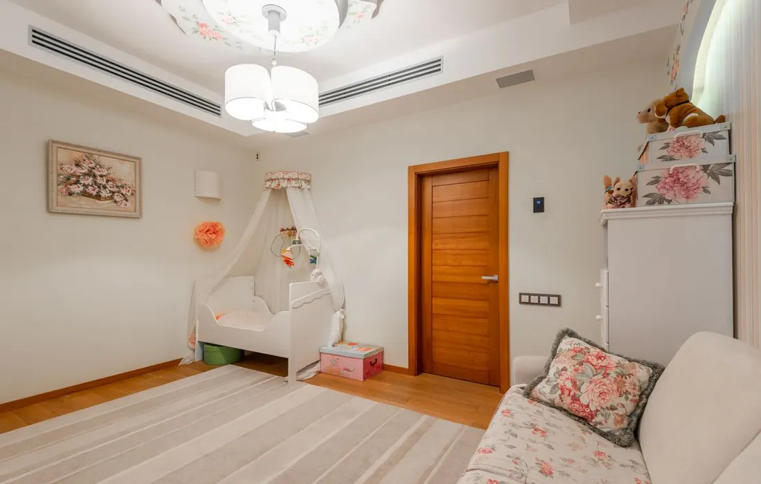 A nursery with a cot and wooden interior door.