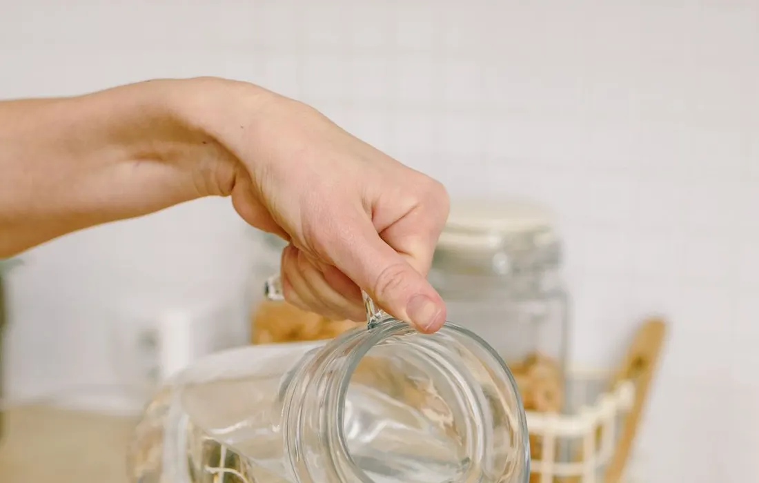 Hands pouring water from a pitcher into a glass.