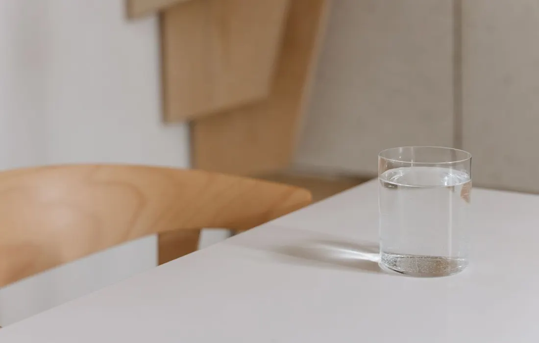A glass of water on a wooden table indoors.