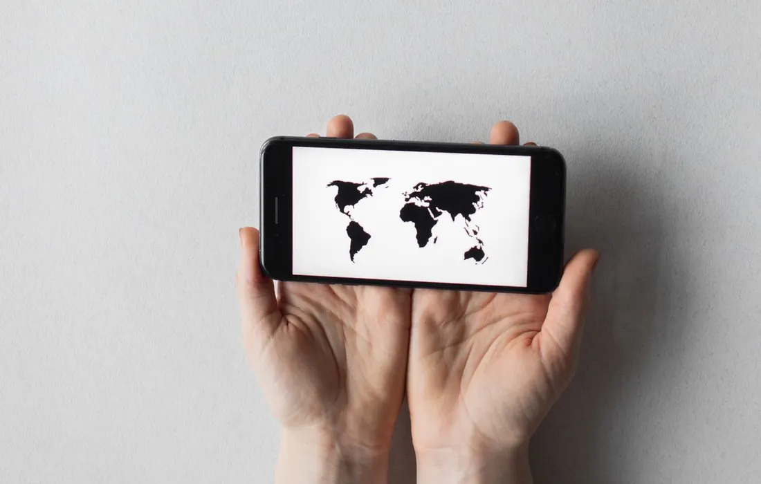 Hands holding a smartphone displaying a world map.