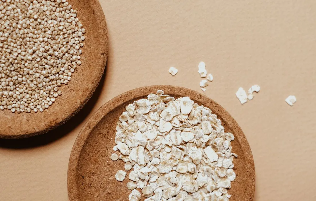 Oats and grains arranged in bowls on a brown background.