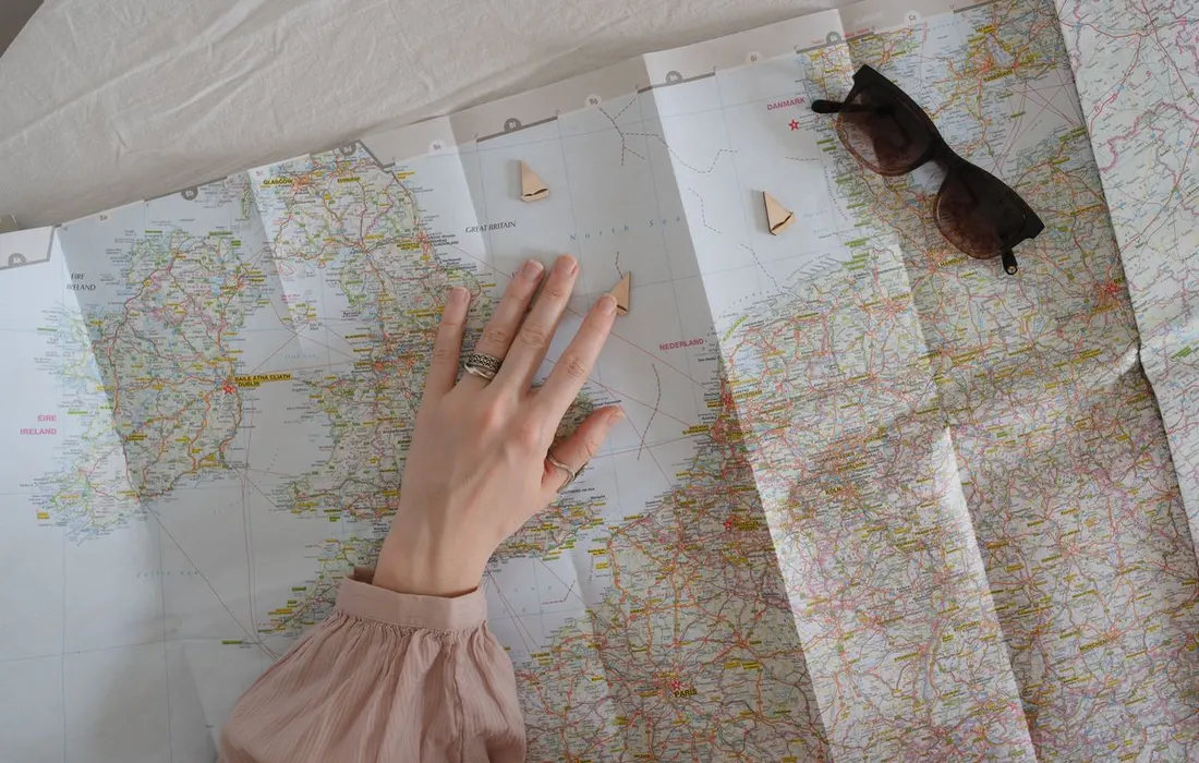 A hand resting above a paper travel map.