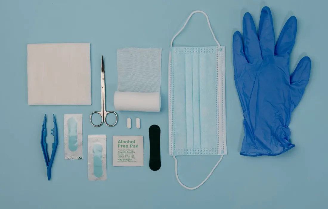 Gloves, scissors and other first aid supplies arranged on a pale blue surface.