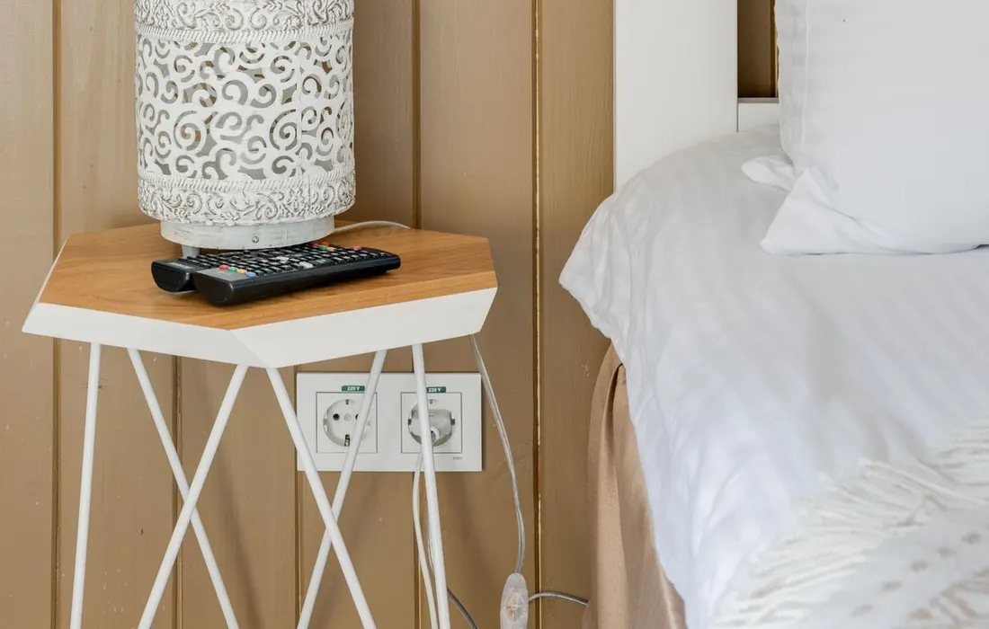 A bedside table with an electric lamp.