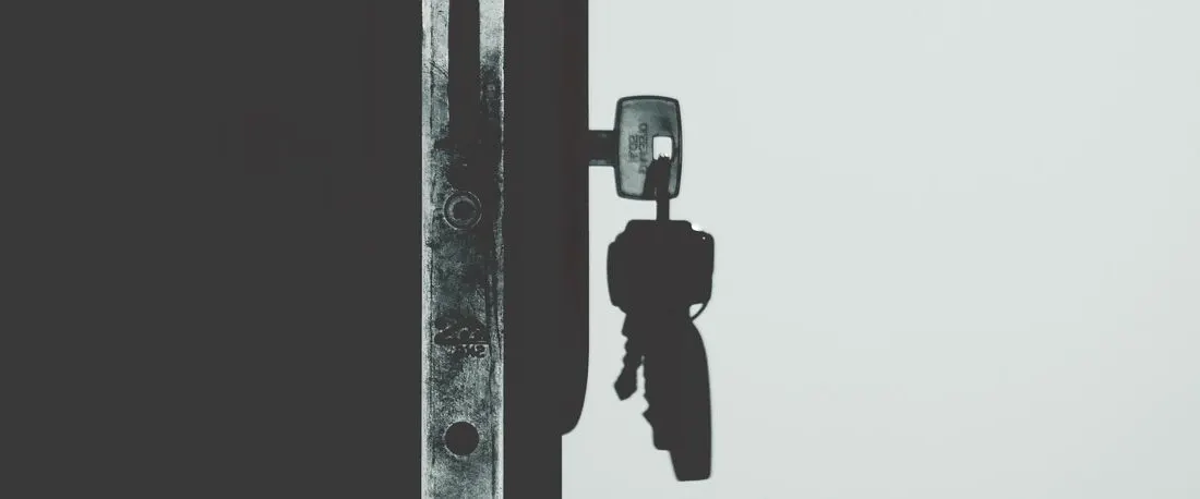 A key inserted in a door lock, photographed in black and white.