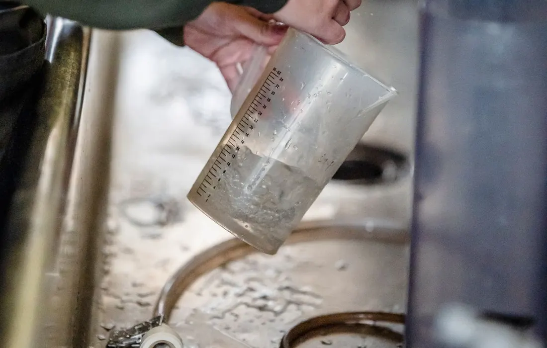Hands filling a measuring jug at a kitchen tap.