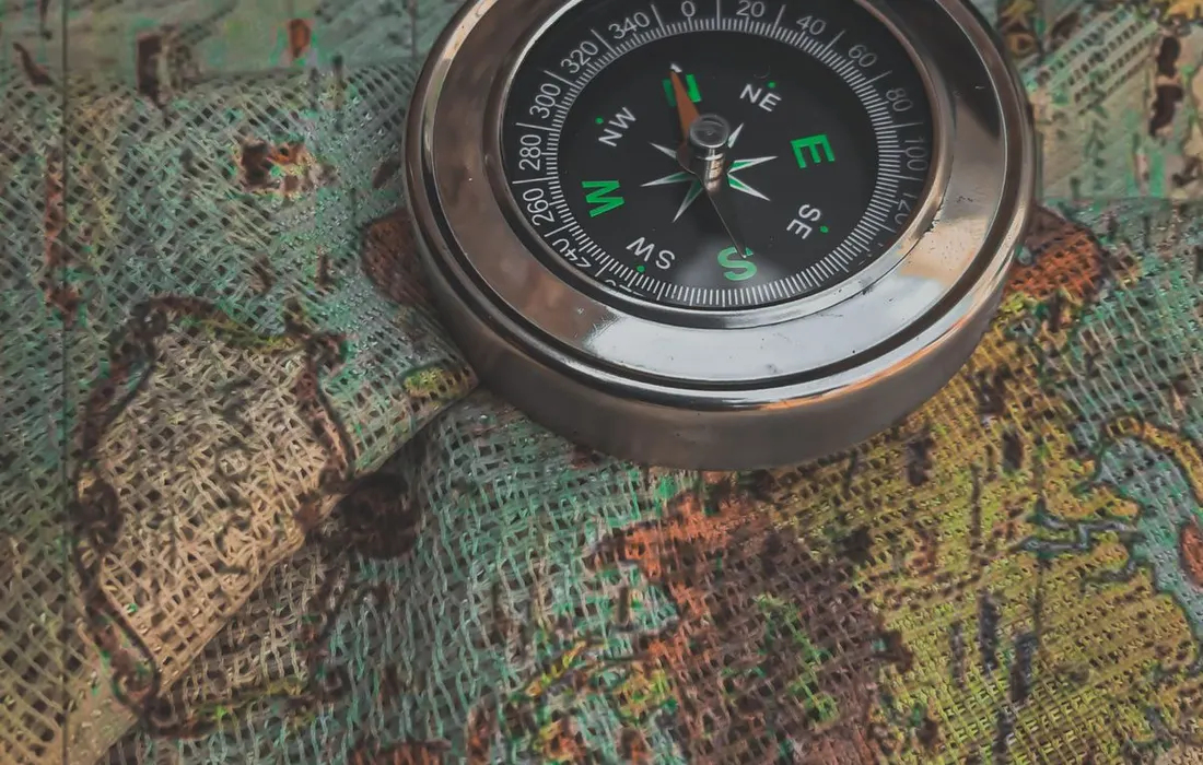 A metal compass resting on a printed world map.