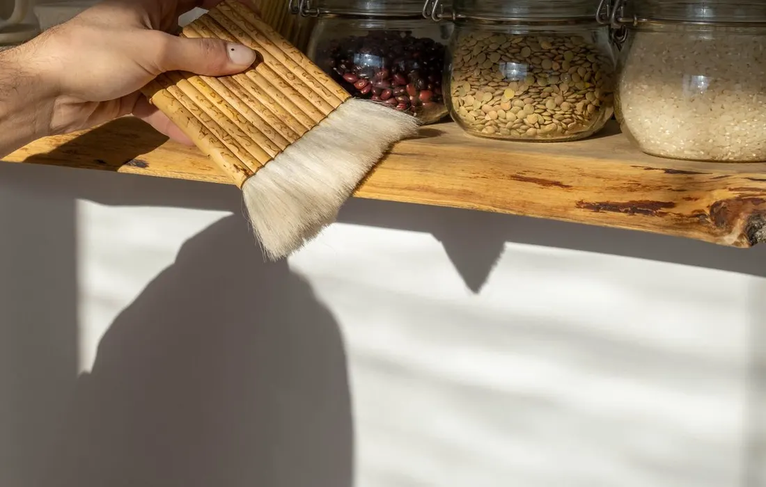 A hand cleaning an organised pantry shelf.