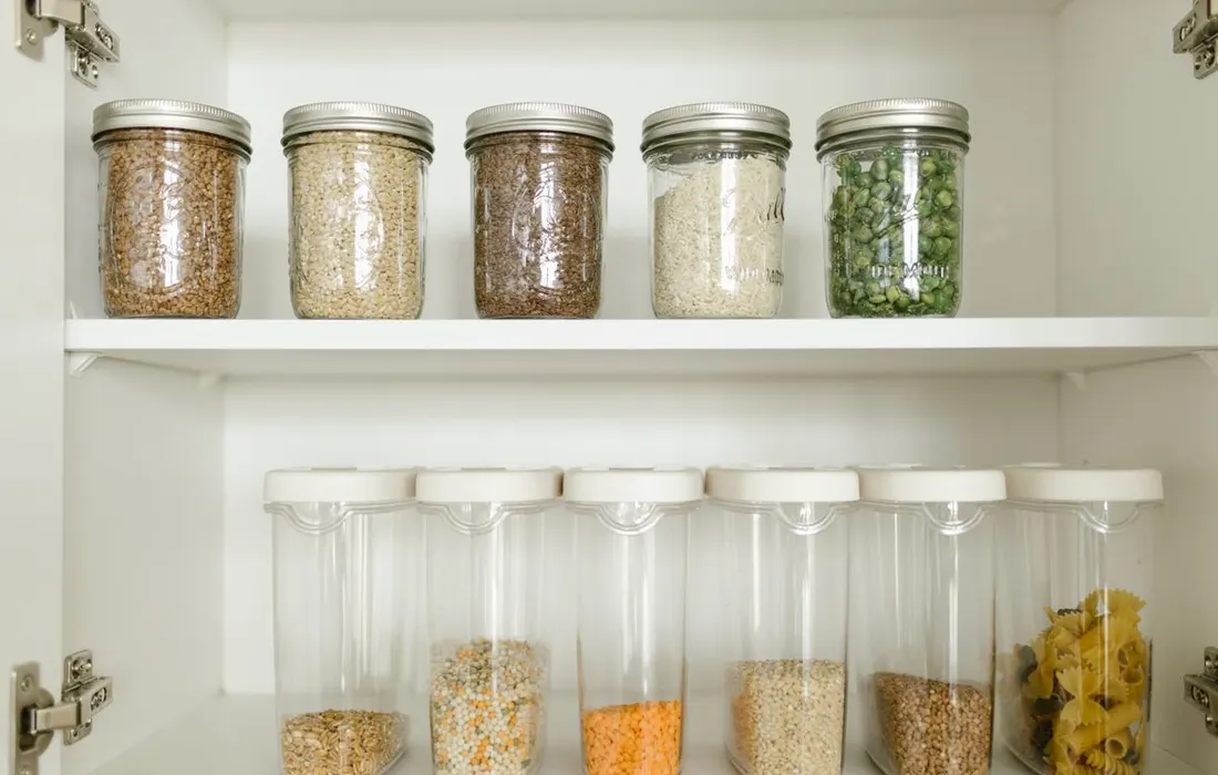 A pantry shelf with dry foods in labelled containers.
