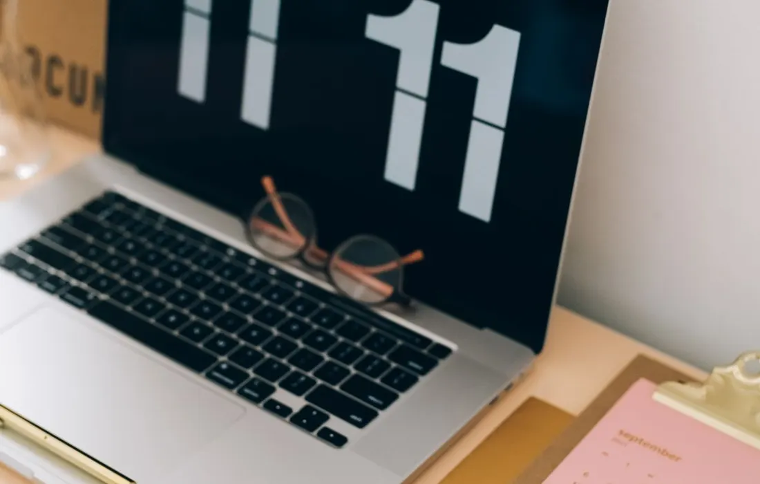A clipboard calendar beside a laptop and glasses.