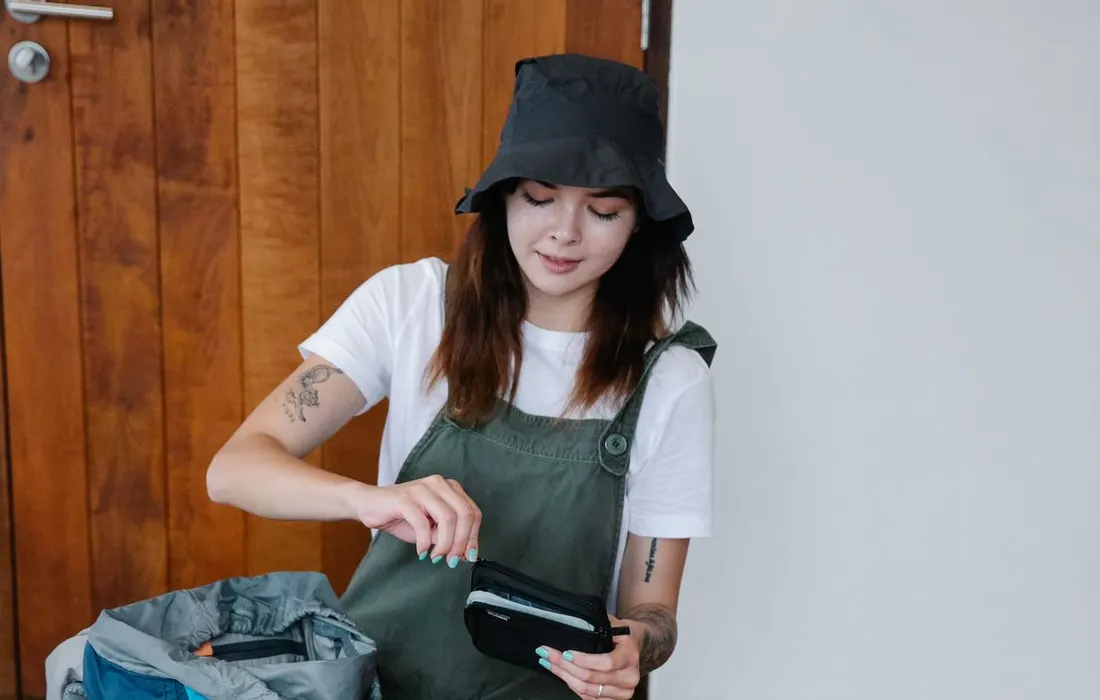A person organising belongings in a backpack indoors.