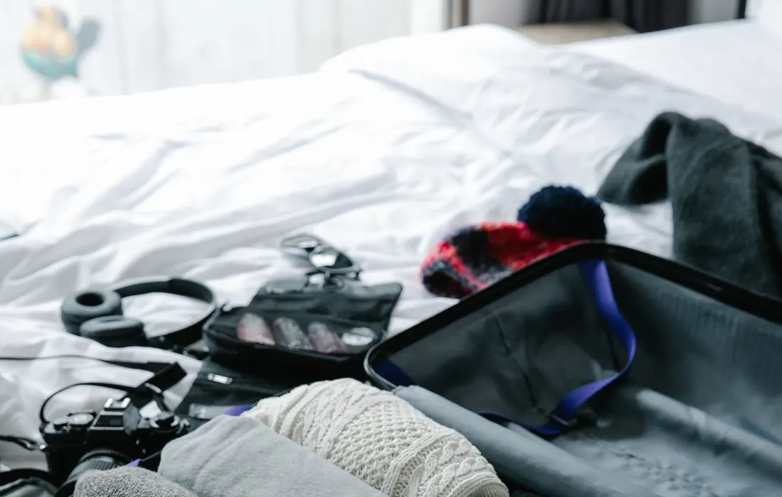 Clothing packed neatly inside an open suitcase on a bed.