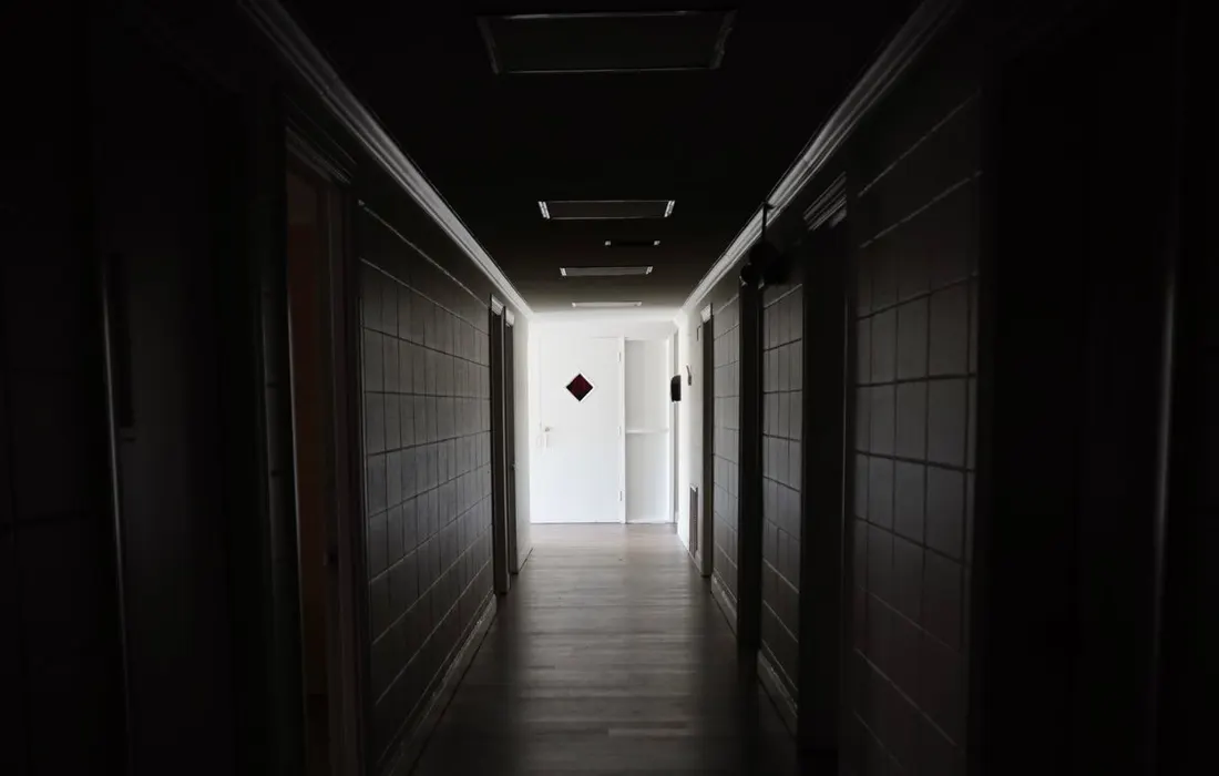 An empty indoor hallway leading towards a closed door.